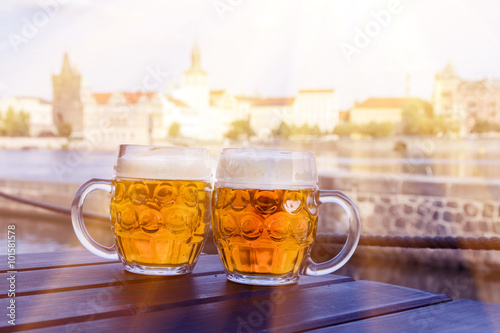 Two mugs of beer on a table against the background of street