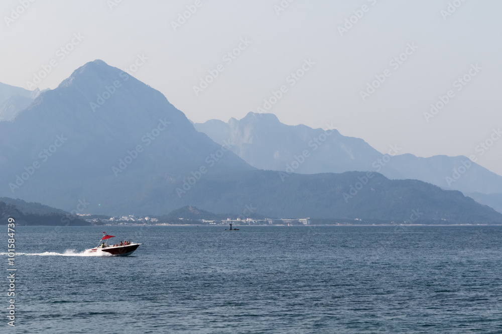 Small boat, ride a water skier, mountains in the background