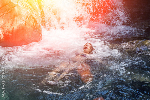 Young woman swimming in the water at the waterfall.