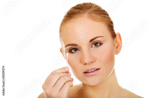 Young woman removing eye makeup with cotton swab