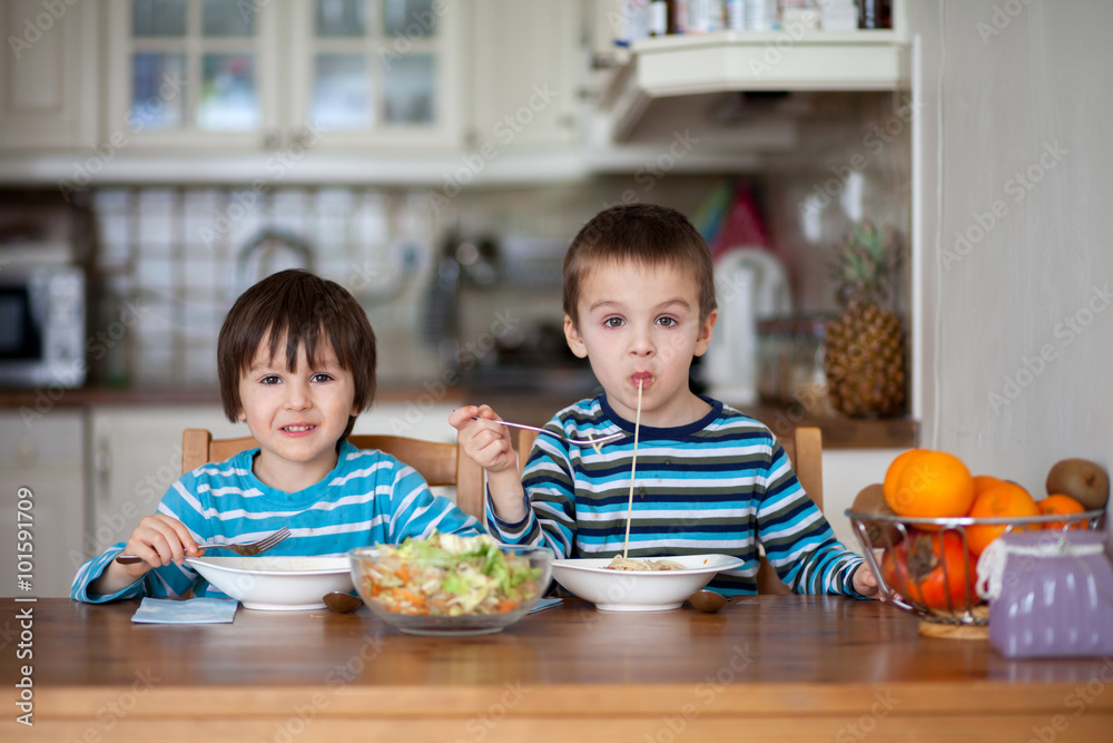 Fototapeta premium Two sweet children, boy brothers, having for lunch spaghetti at