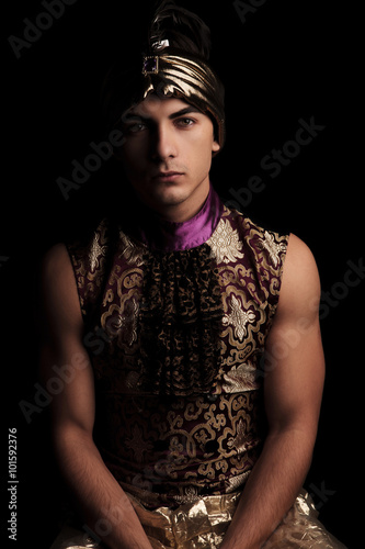 man in alladin costume posing in dark studio background hands do photo