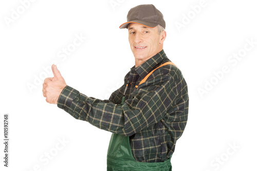 Mature gardener in uniform with thumbs up