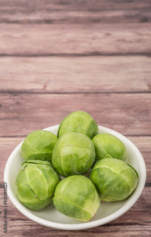 Brussels sprout in white bowl over wooden background Brussels sprout in white bowl over wooden background