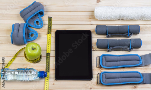 Sport Equipment. Dumbbells,  Ankle Weights, Wrist Weights, Towel, Tape Measure, Apple, Bottle Of Water And Tablet To Workout Plan On Boards. Sport Fitness Background