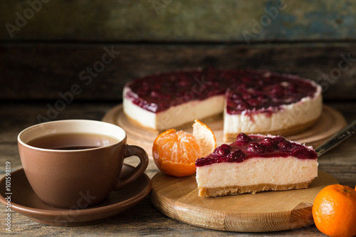 Slice of cheesecake with cherries and cup of tea