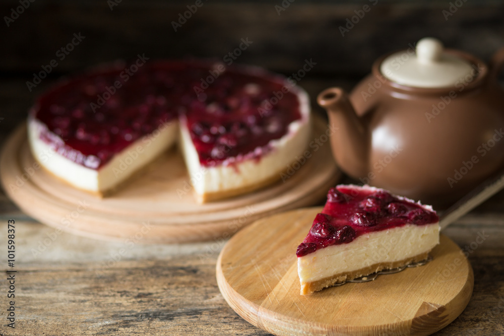 Piece of cheesecake with teapot on wooden table