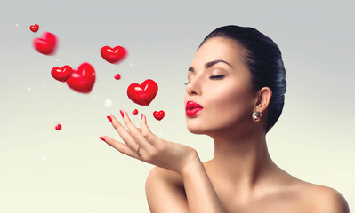 Beauty woman with perfect make up blowing valentine hearts