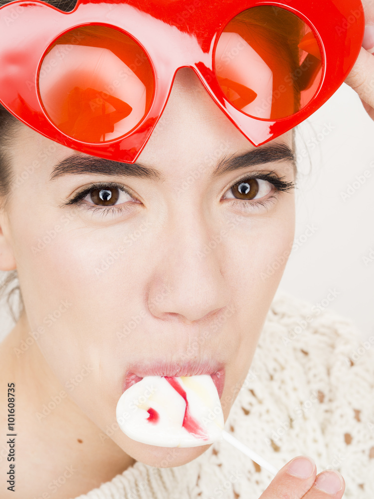 Φωτογραφία Valentine's day portrait of an attractive young brunette girl with heart shaped glasses and heart shaped lollipop