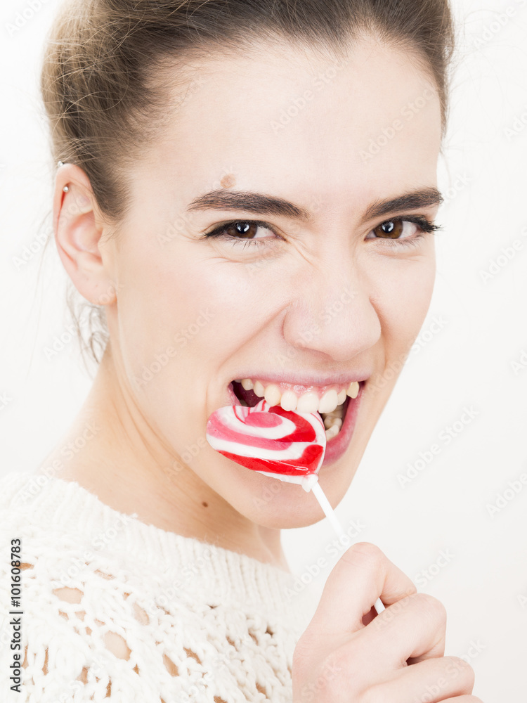 Φωτογραφία Valentine's day portrait of an attractive young brunette girl who bites heart shaped lollipop