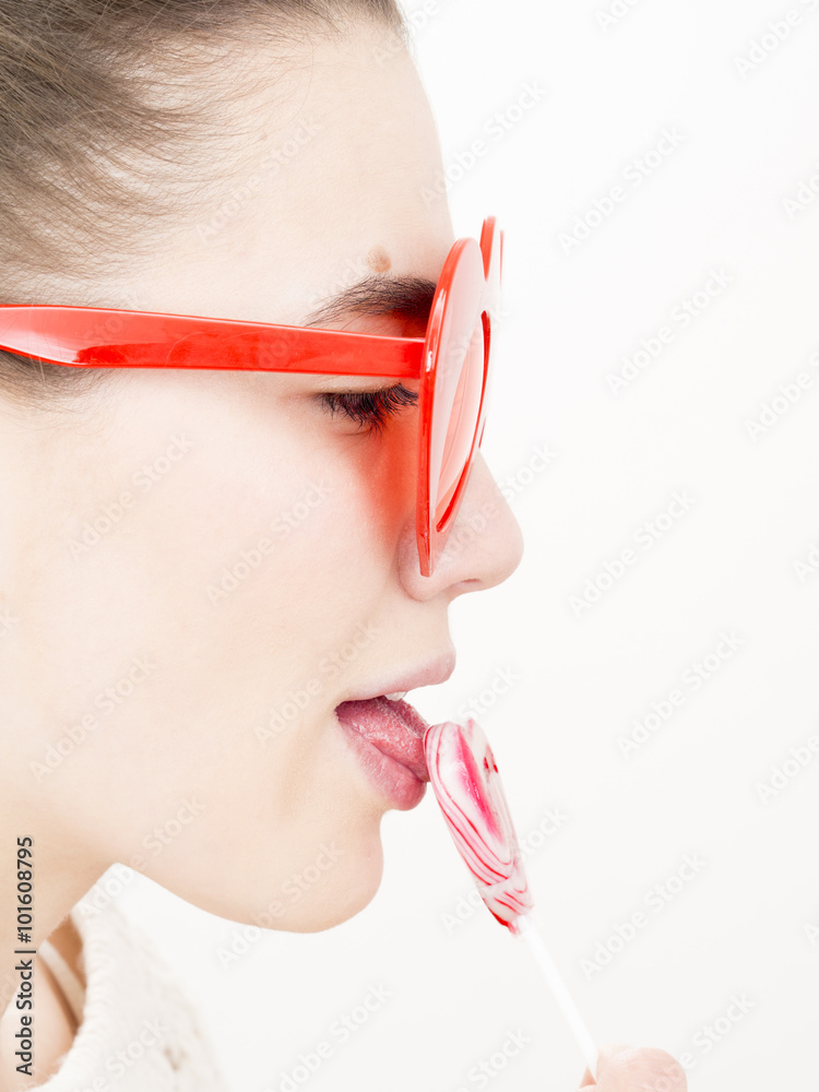 Φωτογραφία Valentine's day portrait of an attractive young brunette girl with heart shaped glasses and heart shaped lollipop