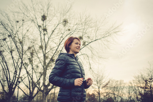 Running young girl jogging in a winter fleece in a city park.Health and fitness concept