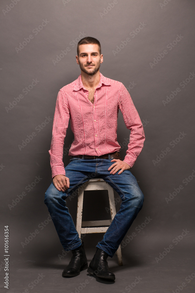 Handsome man sitting on a chair in studio Handsome man sitting on a chair in studio