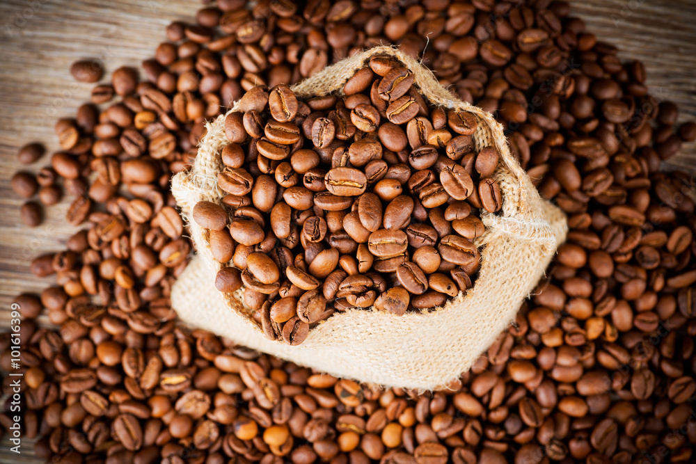 The sack of coffee beans on wooden background