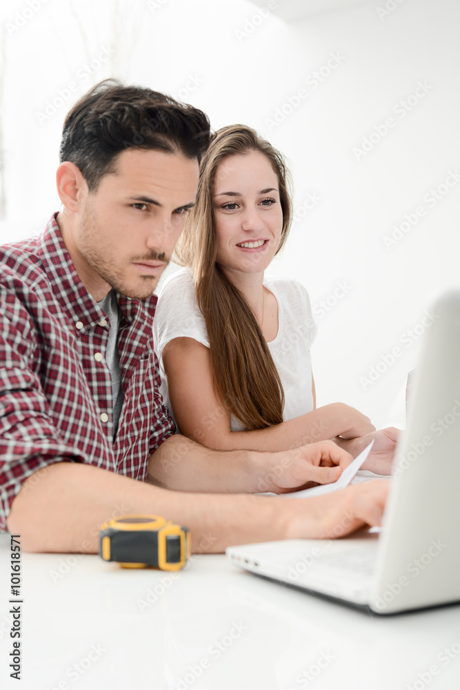 young couple planning decoration project of their new home with blueprint young couple planning decoration project of their new home with blueprint