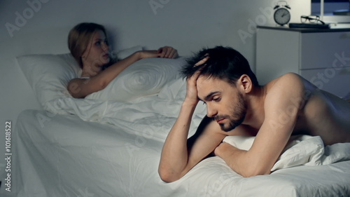 Sad young couple lying apart in bed at night sleepless and thoughtful 