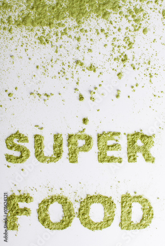 Word superfood piled of .green powder of barley grass on white background.