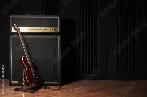 Red electric guitar and classic amplifier on a dark background photo