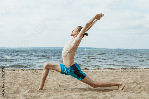 Fototapeta Naklejka Na Ścianę i Meble -  Naked man doing yoga on the beach