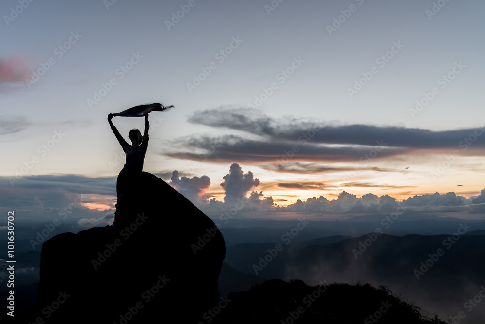 Fotografie Silhouette of women spreading hand on the top of mountain at sun
