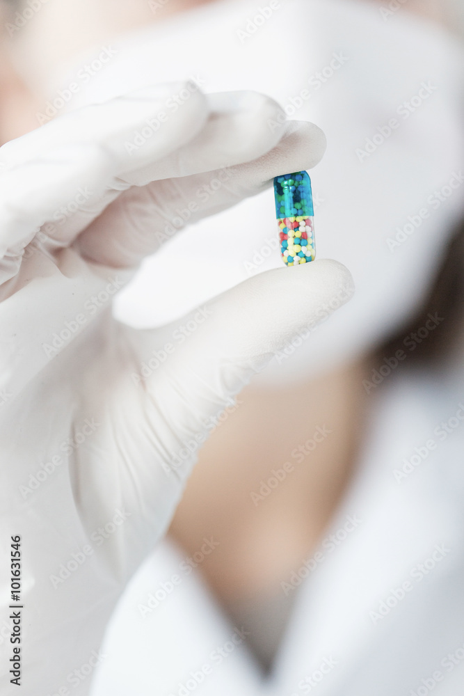 close up of scientist holding pill in lab
