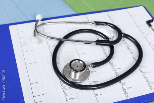 Stethoscope laying on a blue clipboard with a medical chart