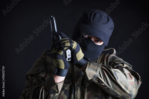 Antiterrorist looking at camera, holding a gun, studio shot photo