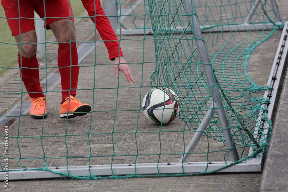 Φωτογραφία fußballer holt sich einen fußball aus dem fußballtor