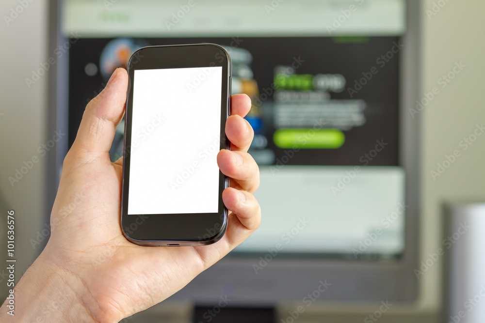 Closeup of man's hand holding smartphone in front of computer screen. Closeup of man's hand holding smartphone in front of computer screen.