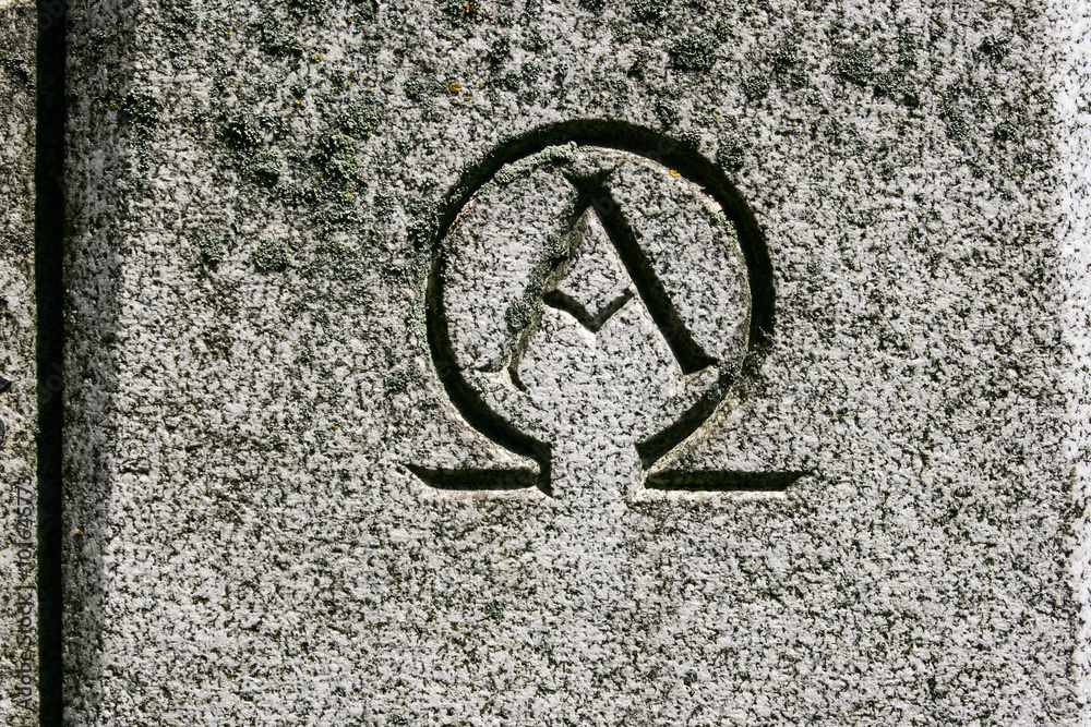 Alpha omega symbol carved in grey granite stone Stock Photo