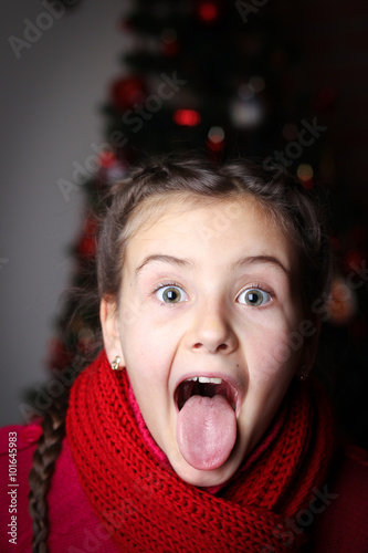 little girl with pigtails in red knitted sweater against the bac