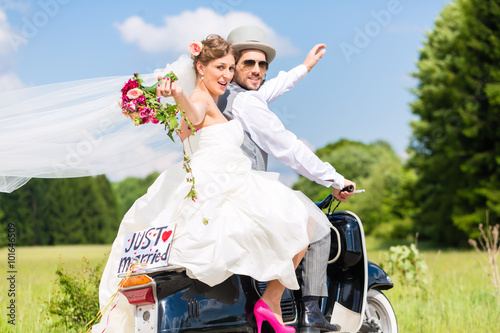 Fotografia Hochzeit Bräutigam und Braut fahren mit Motorroller und haben Spaß
