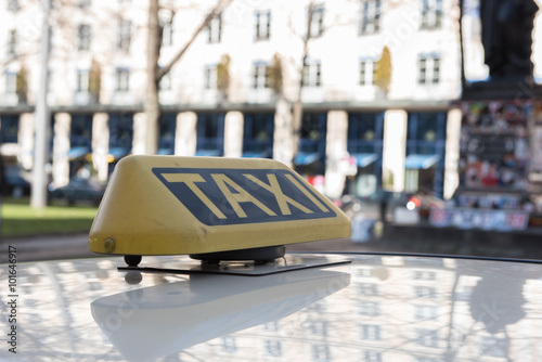taxi sign on the roof of a car standing in street