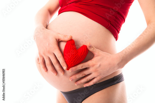 pregnant woman's belly with red knitted heart, concept of love,