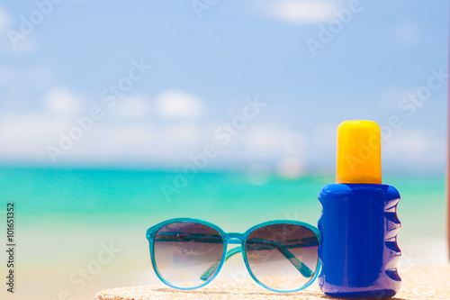 Sunscreen and sunglasses on sand at tropical beach