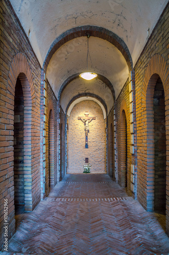 Dark artistic old cross on a shaded rough textured brick wall in photo