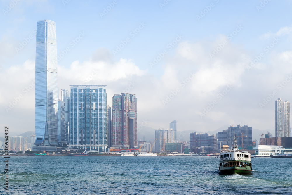 Ferry and International Commerce Centre (ICC) skyscraper and other buildings in the background in Kowloon, Hong Kong, China. Ferry and International Commerce Centre (ICC) skyscraper and other buildings in the background in Kowloon, Hong Kong, China.