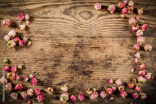 Dried rose flowers on wooden background