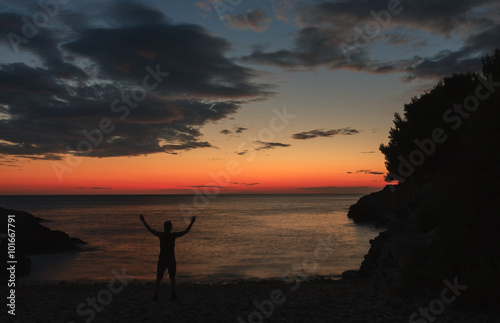 Silhouette of praying man after sea sunset