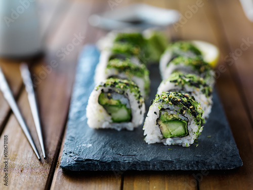 healthy kale, avocado and cucumber sushi roll on slate serving tray