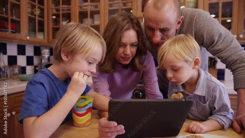 Portrait of a lovely white family huddled over a handheld tablet Portrait of a lovely white family huddled over a handheld tablet