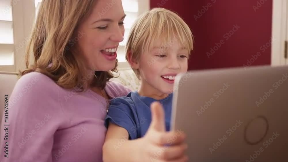 Handsome young boy looking at a laptop computer screen with mom Handsome young boy looking at a laptop computer screen with mom