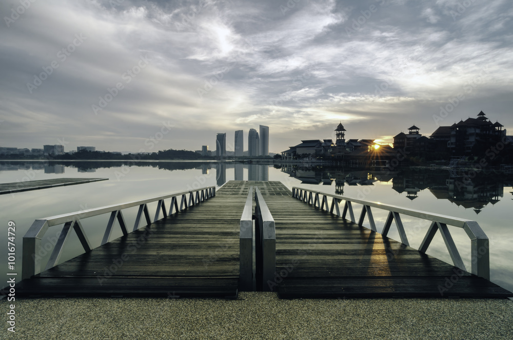 Obraz premium beautiful morning near the lakeside, modern building and wooden jetty. dramatic clouds and sunlight