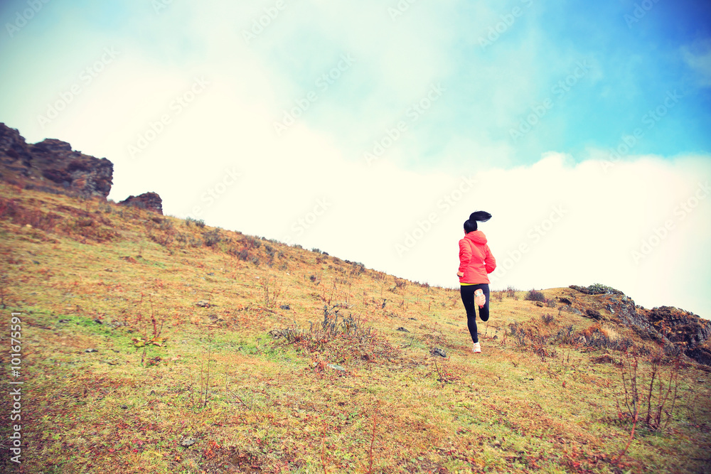 young woman trail runner running on mountain peak..