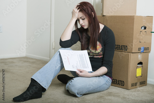 Woman who appears sad with moving boxes and eviction note