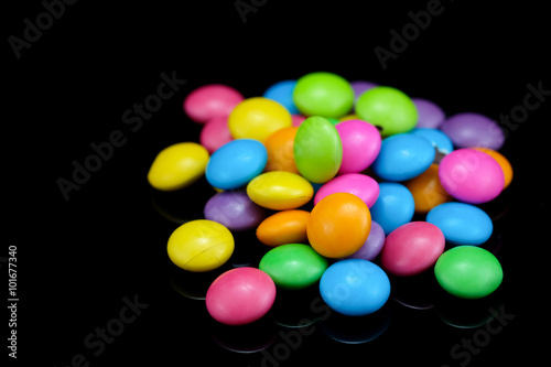 Chocolate candy in many colors on a black background.