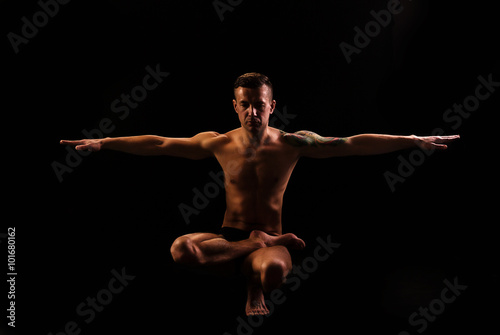 Young strong man practices yoga and gymnastics, Eagle posture, balance