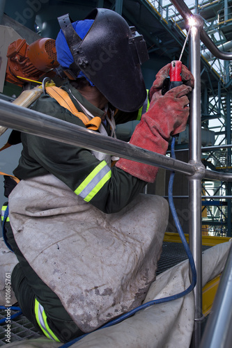 Worker dressed in protective uniform welding metal frame