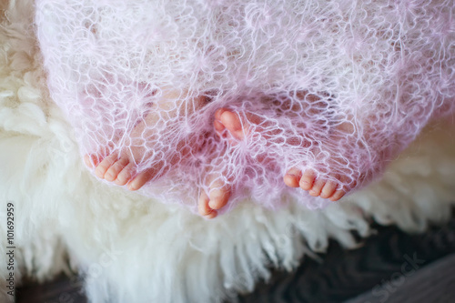 Small feet newborn twins wrapped in a blanket