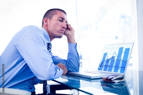 Composite image of tired businessman looking at his laptop